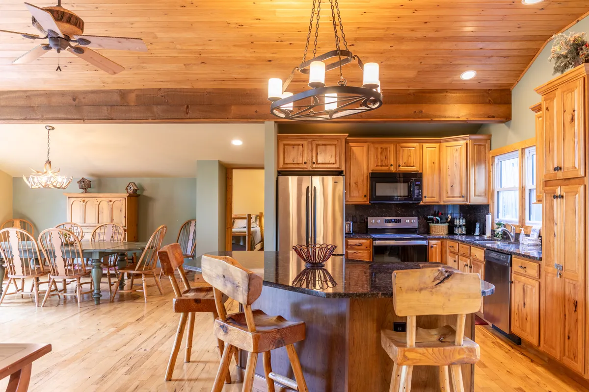 A spacious, open kitchen and dining area with a central island, warm wooden cabinetry, elegant light fixtures, and a visible connection to the dining space. The layout invites socializing and shared meals, with ample room for family and friends to gather.