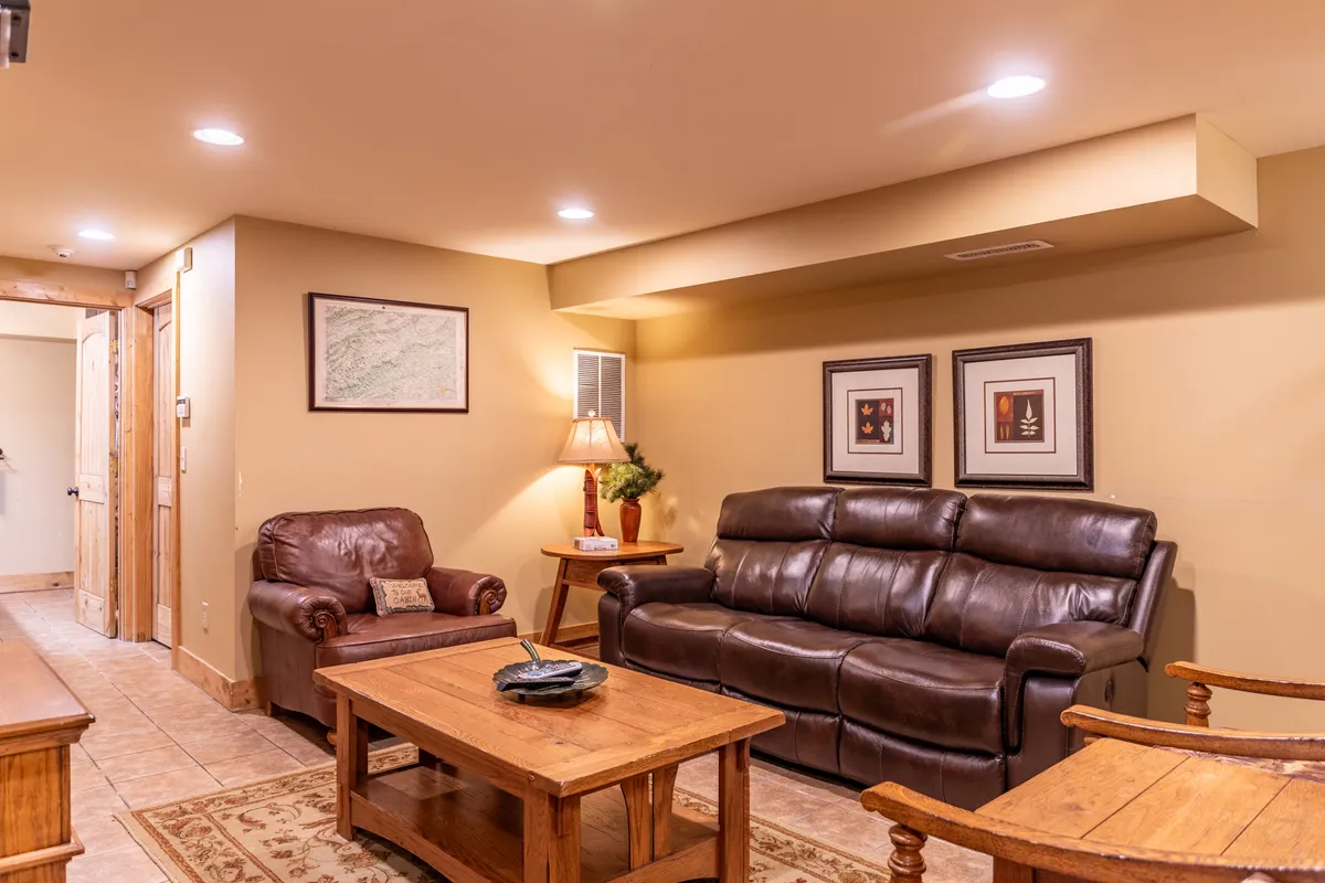 A warm and inviting room with reclining sofas, a wooden coffee table, framed artwork, and a soft lamp glow—ideal for reading, relaxing, or enjoying quiet moments together as a family.